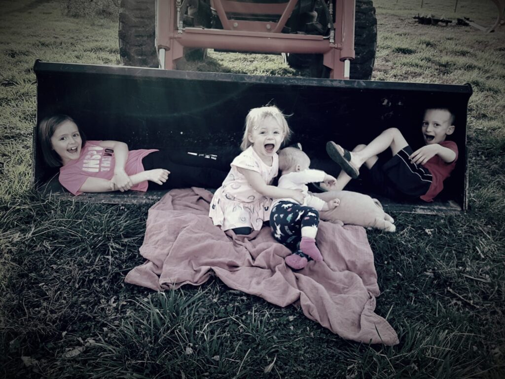 four kids in a tractor bucket on the ground