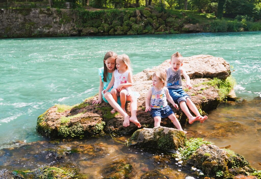 four kids posing in front of a river