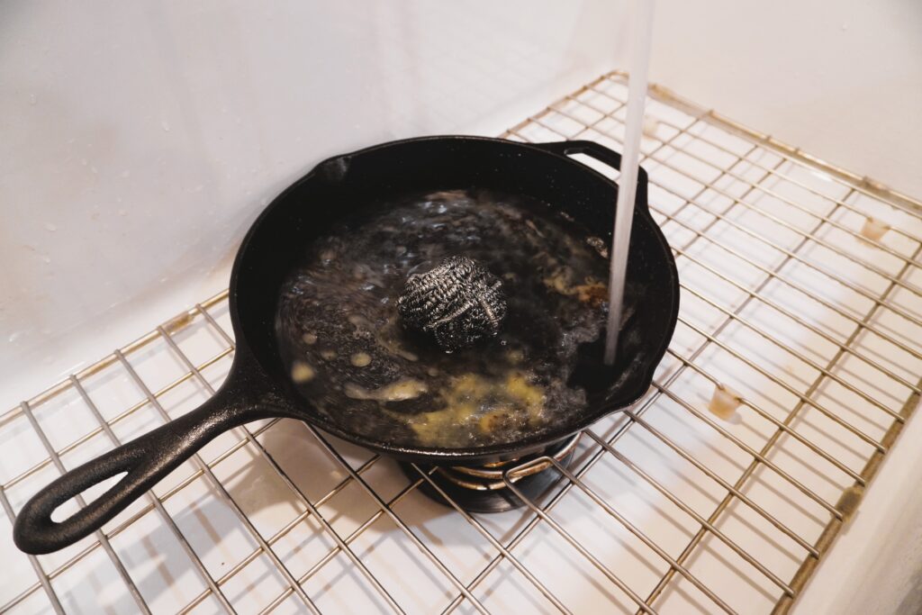 cast iron skillet in a farmhouse sink filling with water
