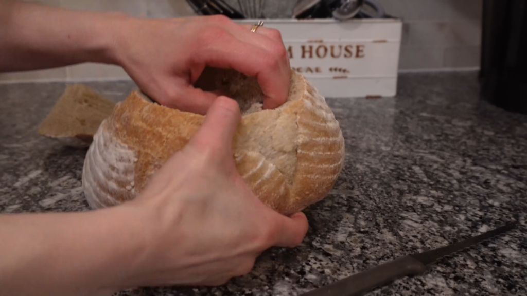 pulling bread out of sour dough bread bowl