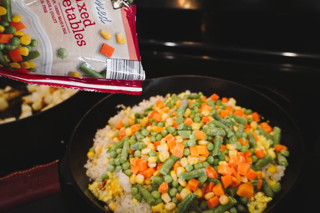 mixed vegetables being poured into a cast iron skillet