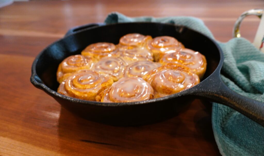 iced cinnamon rolls in a cast iron skillet