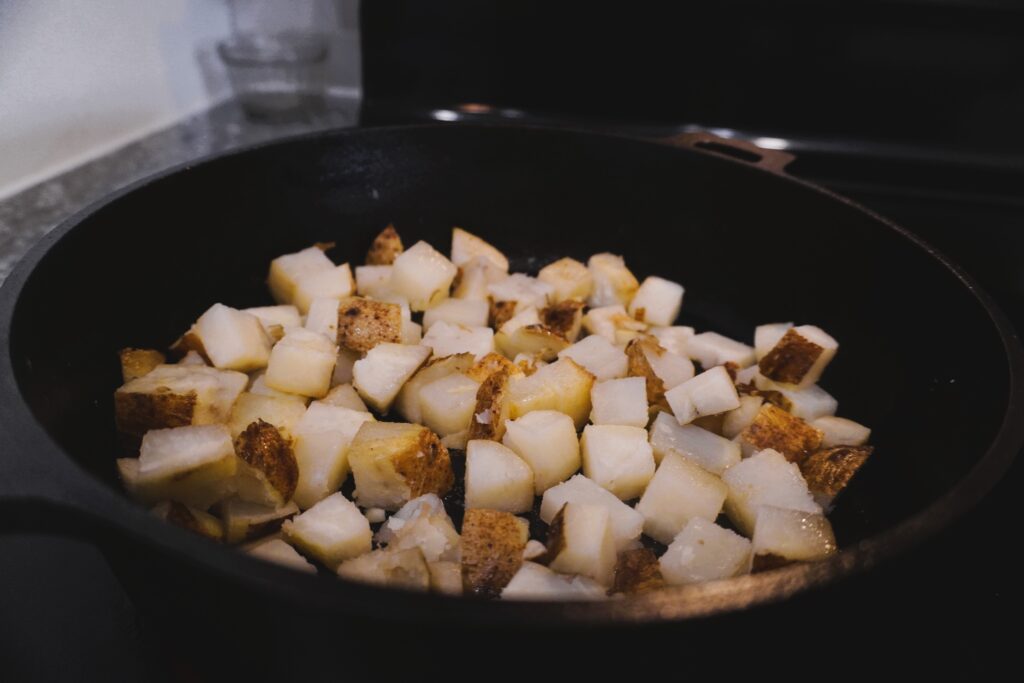 potatoes frying in a cast iron skillet