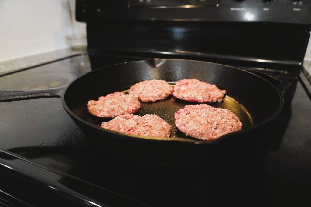 raw sausage cooking in a cast iron skillet