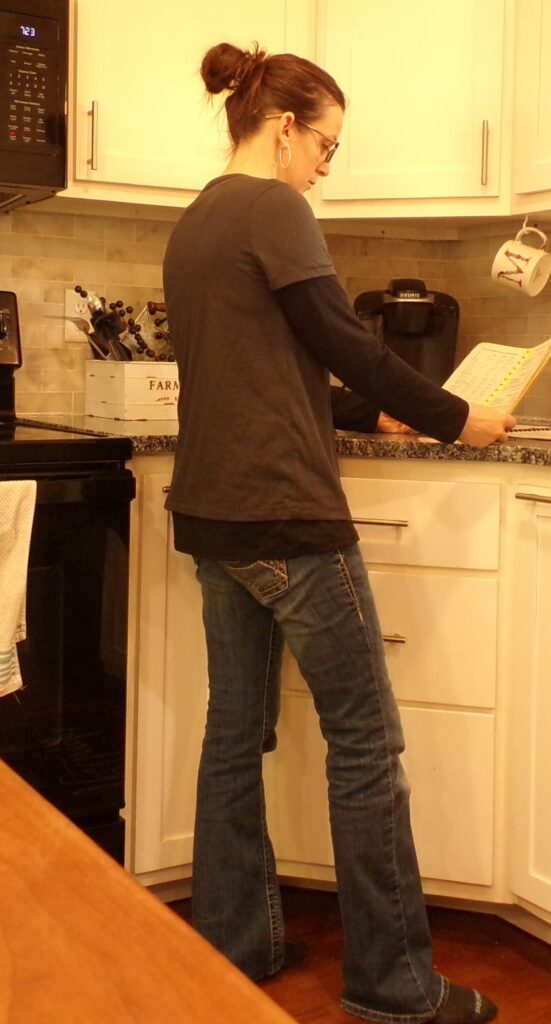 Woman standing in a kitchen looking at a cookbook
