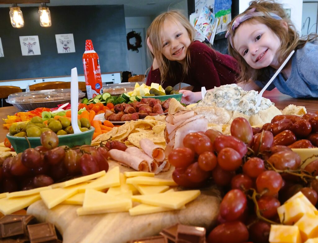 Charcuterie food on a counter with two kids smiling at the camera