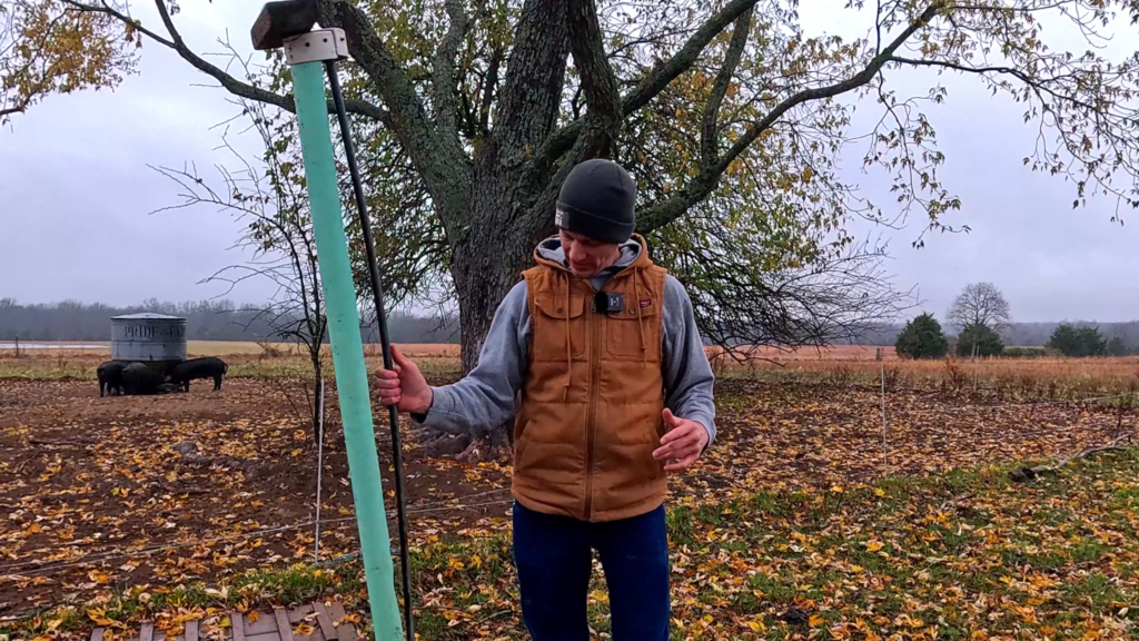 Man holder a homemade chicken feeder in a field