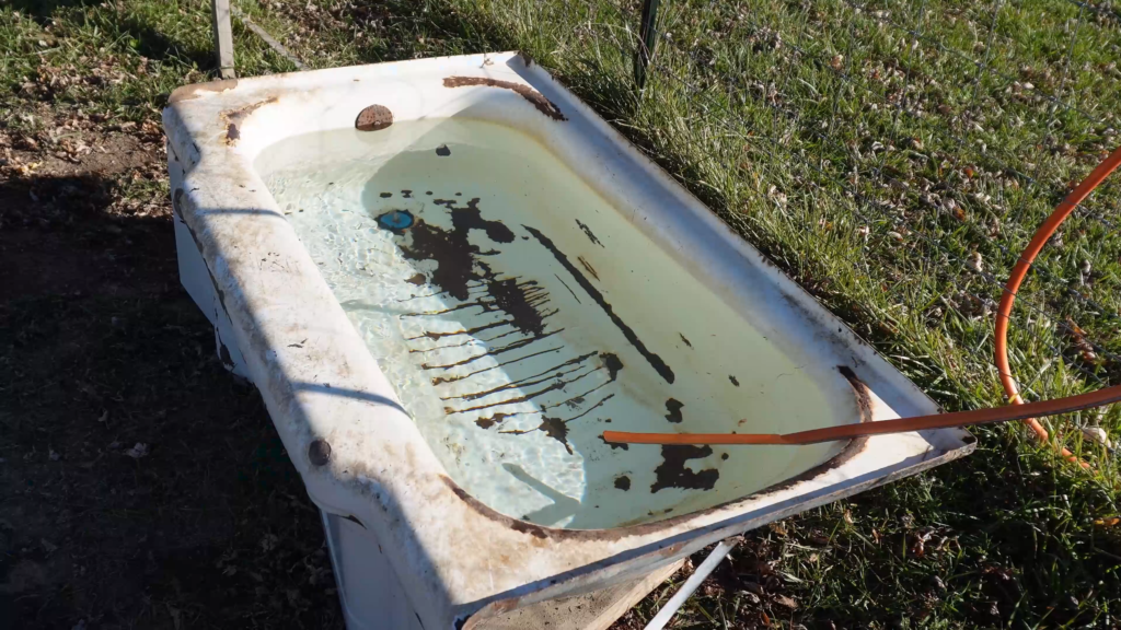 Old bath tub used as a livestock water trough full of water