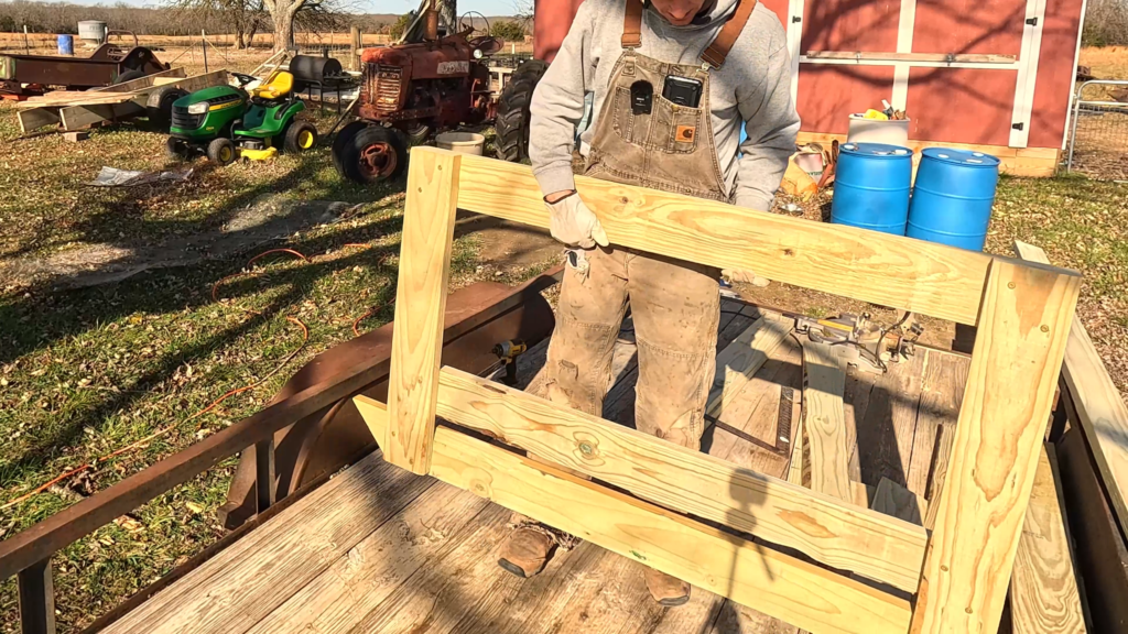 Man holding one end of DIY round bale feeder