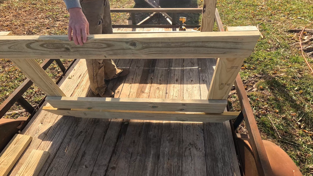 Man holding two end pieces for DIY round bale feeder