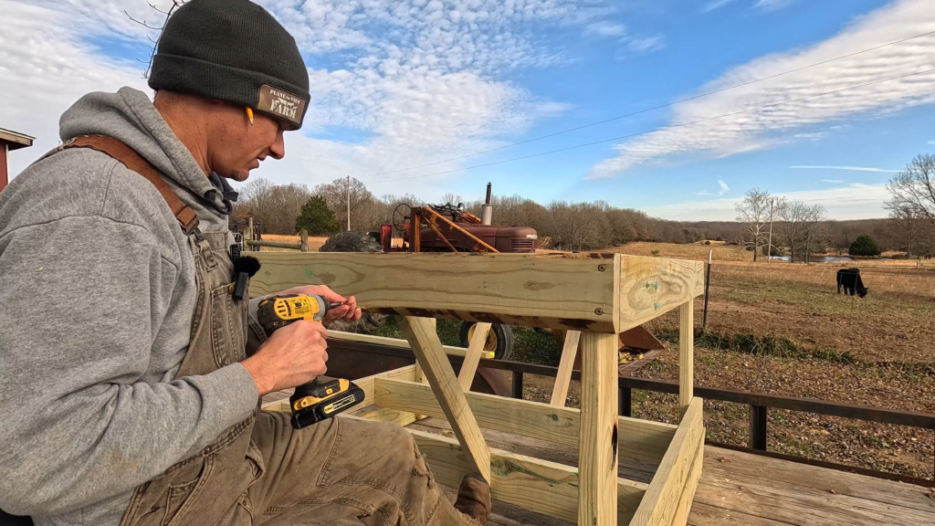 Man drilling screws in a DIY round bale feeder