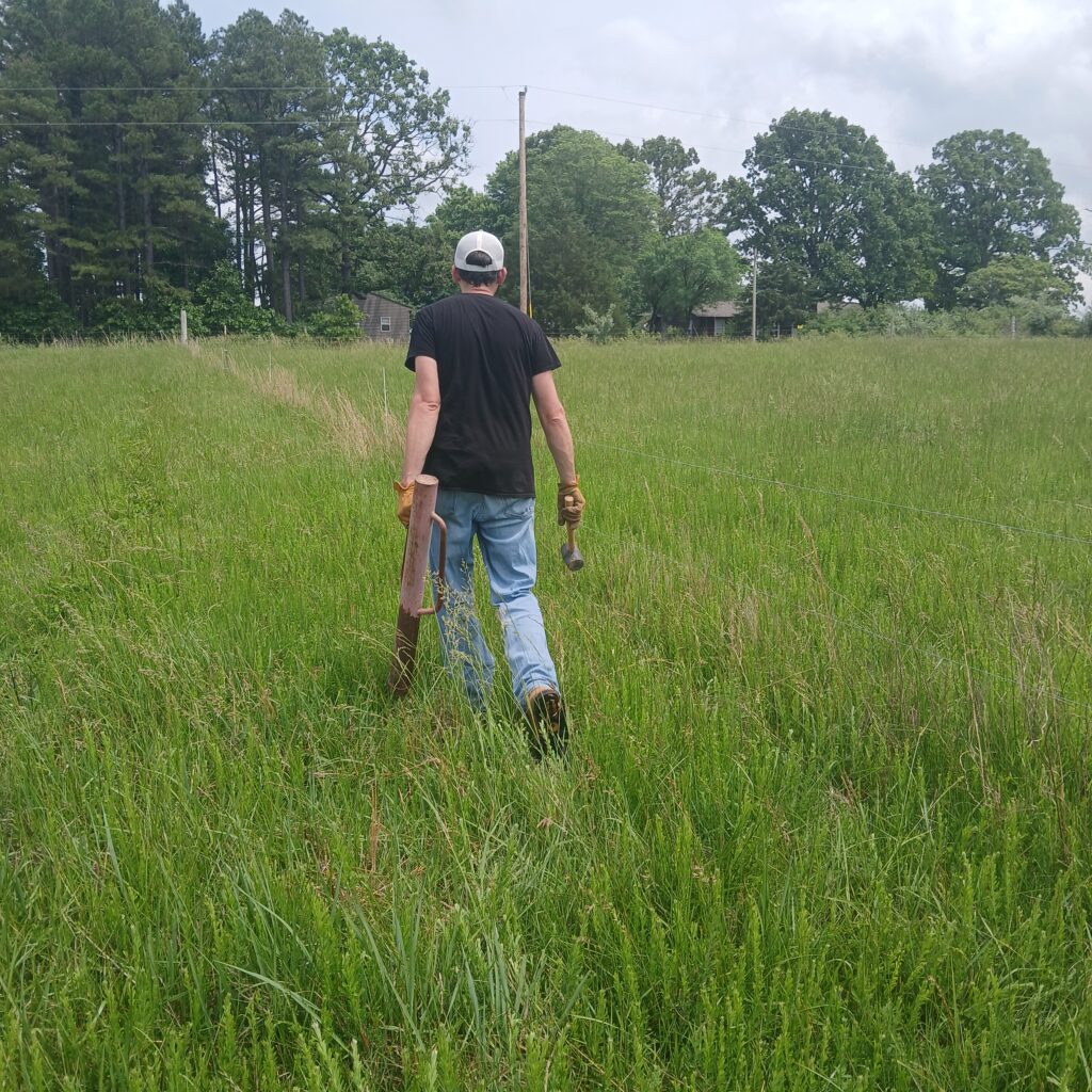 Man carrying fencing supplies in a field